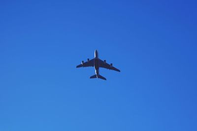 Low angle view of airplane against clear blue sky