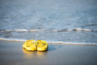 Yelllow flipflop or sandal shoes on beach with motion wave in ao nang, krabi