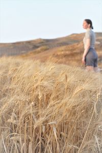 Side view of woman standing on field against sky