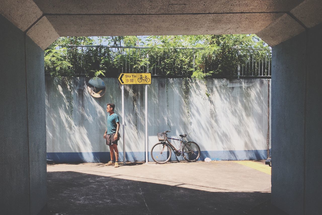 bicycle, day, built structure, one person, architecture, casual clothing, real people, full length, outdoors, transportation, lifestyles, standing, building exterior, water, tree, nature, people