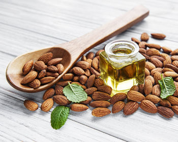 Almond oil and almonds on white wooden background. top view