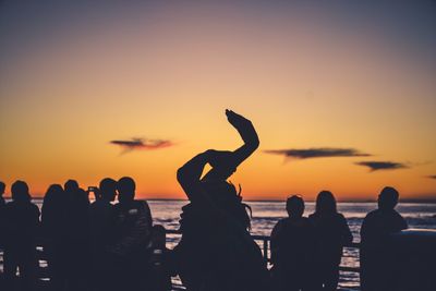 Silhouette people on beach against sky during sunset