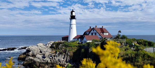 Lighthouse by sea against sky