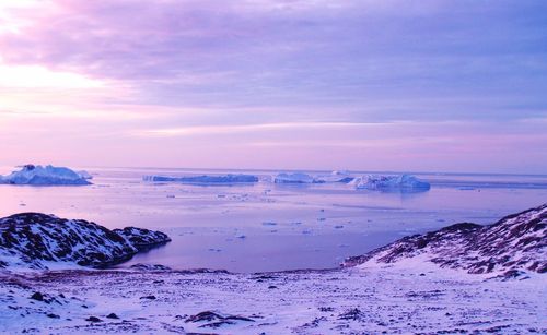 Icebergs on sea against sky during sunset