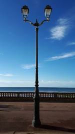 Street light by sea against sky