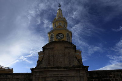 Low angle view of clock tower against cloudy sky