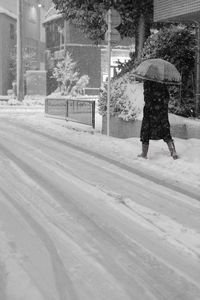 Rear view of man walking on snow covered road