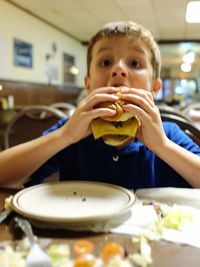Boy eating cheeseburger at restaurant