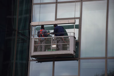 Low angle view of window washers cleaning glass building