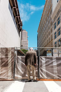 Rear view of man in city against sky