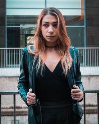 Thoughtful woman standing against railing