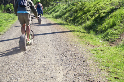 People riding push scooters on footpath