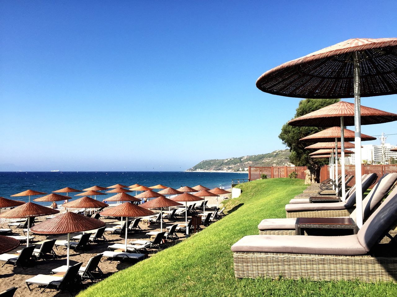 sea, clear sky, horizon over water, beach, water, blue, copy space, beach umbrella, tranquil scene, tranquility, scenics, parasol, thatched roof, shore, lounge chair, sunlight, vacations, sunshade, nature, beauty in nature