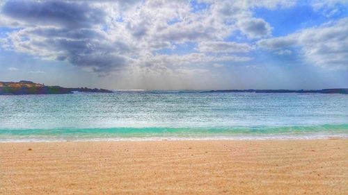 Scenic view of beach against cloudy sky