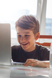 Smiling boy using laptop at home