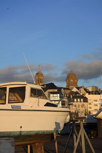 Sailboats moored on sea against buildings in city