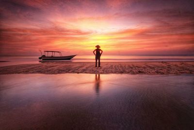 Man standing on beach against sky during sunset