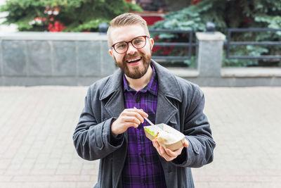 Smiling man eating food outdoors