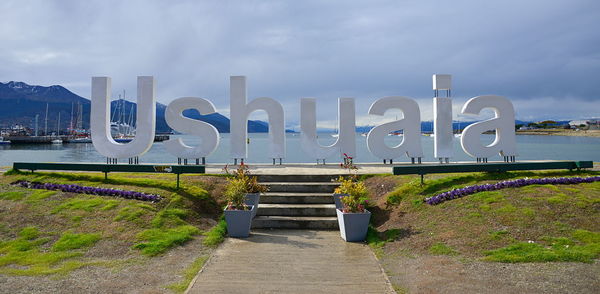 Text on grass against sky in city