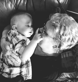 High angle view of grandmother carrying grandson on sofa at home