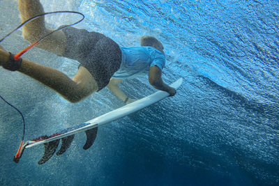 Underwater view of young man surfing in blue waters of south male atoll