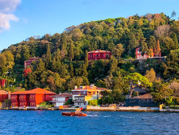 Scenic view of river by trees and houses against sky