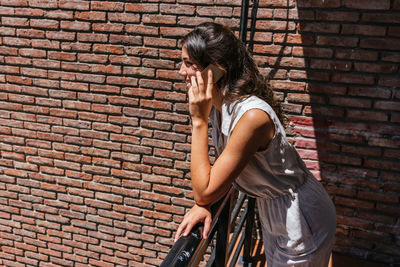 Side view of woman standing against brick wall