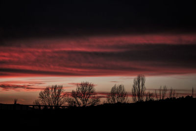 Silhouette landscape against dramatic sky during sunset