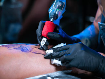 Cropped image of tattooist making tattoo on customer