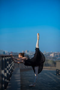 Woman standing on railing against sky