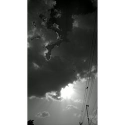 Low angle view of power lines against cloudy sky