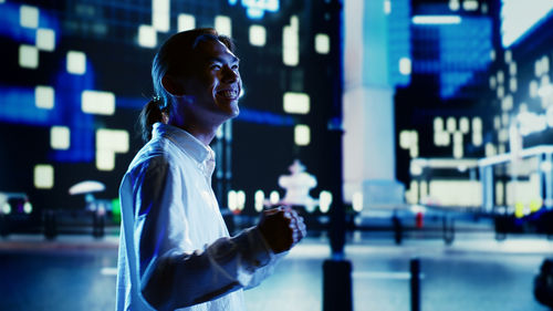 Side view of young woman standing in city at night