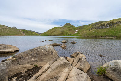 Rocks by lake against sky