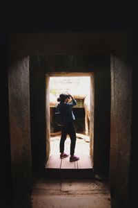 Rear view of woman standing in abandoned building