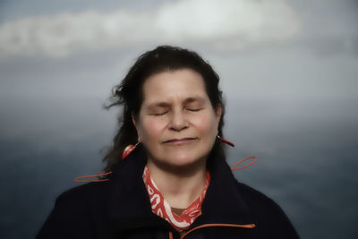 Portrait of smiling young woman against sky