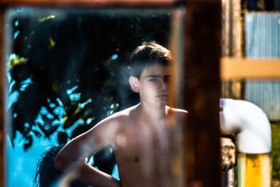 Portrait of shirtless young man reflecting on mirror