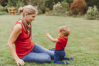 Side view of boy sitting on grass against plants