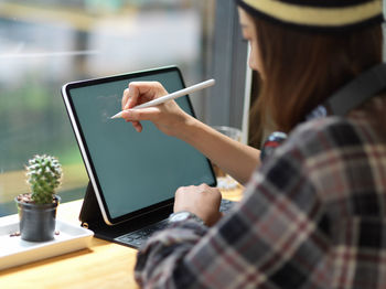 Midsection of woman using digital tablet in cafe