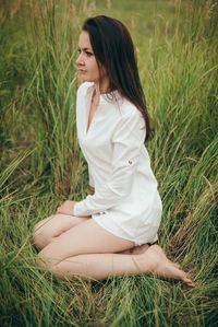 Young beautiful woman sitting on grassy field