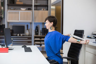 Side view of man using laptop at office