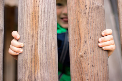 Close-up of boy holding wooden railing
