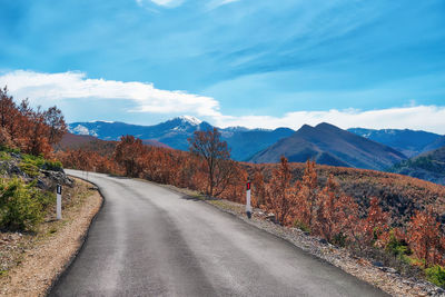 Empty road along landscape and mountains against sky