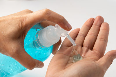 Close-up of hand holding glass bottle against white background