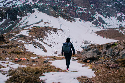 Rear view of man walking on snowcapped mountain