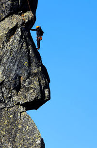 Low angle view of cliff against blue sky