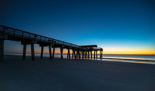 Pier over sea against clear sky during sunset