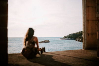 Woman sitting on beach looking at sea