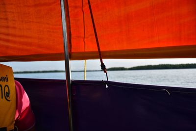Sailboat sailing in sea against orange sky