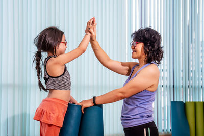 Side view of two women standing against wall