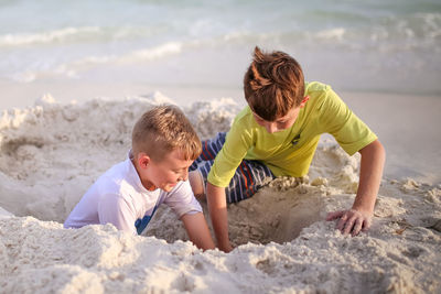 Brothers digging hole at beach